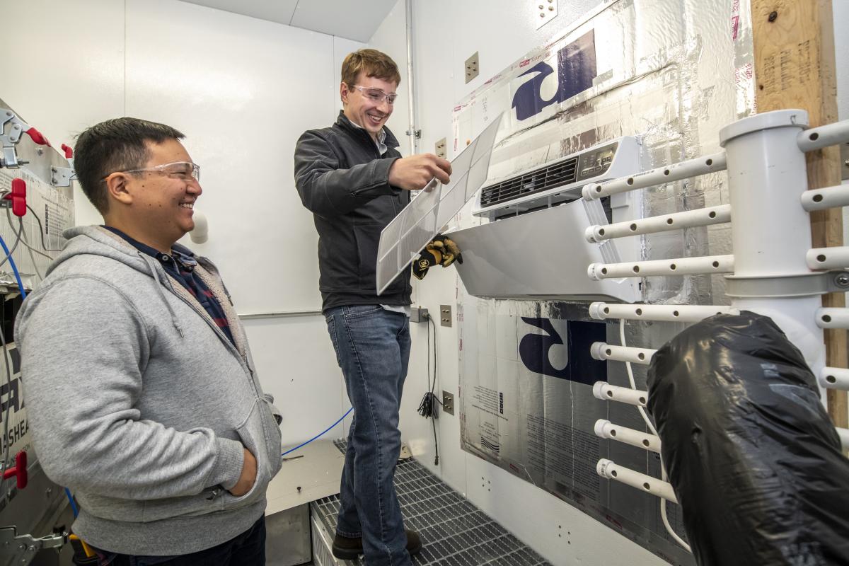Tom Burke and Kevin Zhou test an air conditioner.